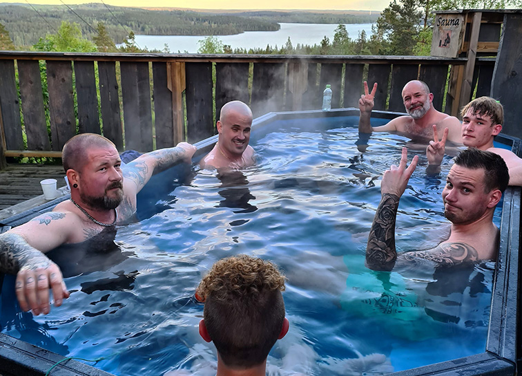 Grupp som badar i vedeldat bad med utsikt