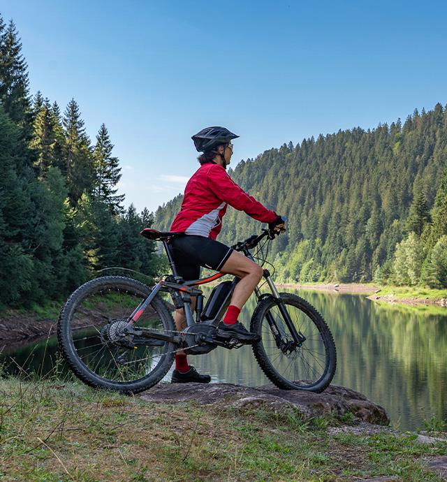 En kvinna med cykel står vid en sjö